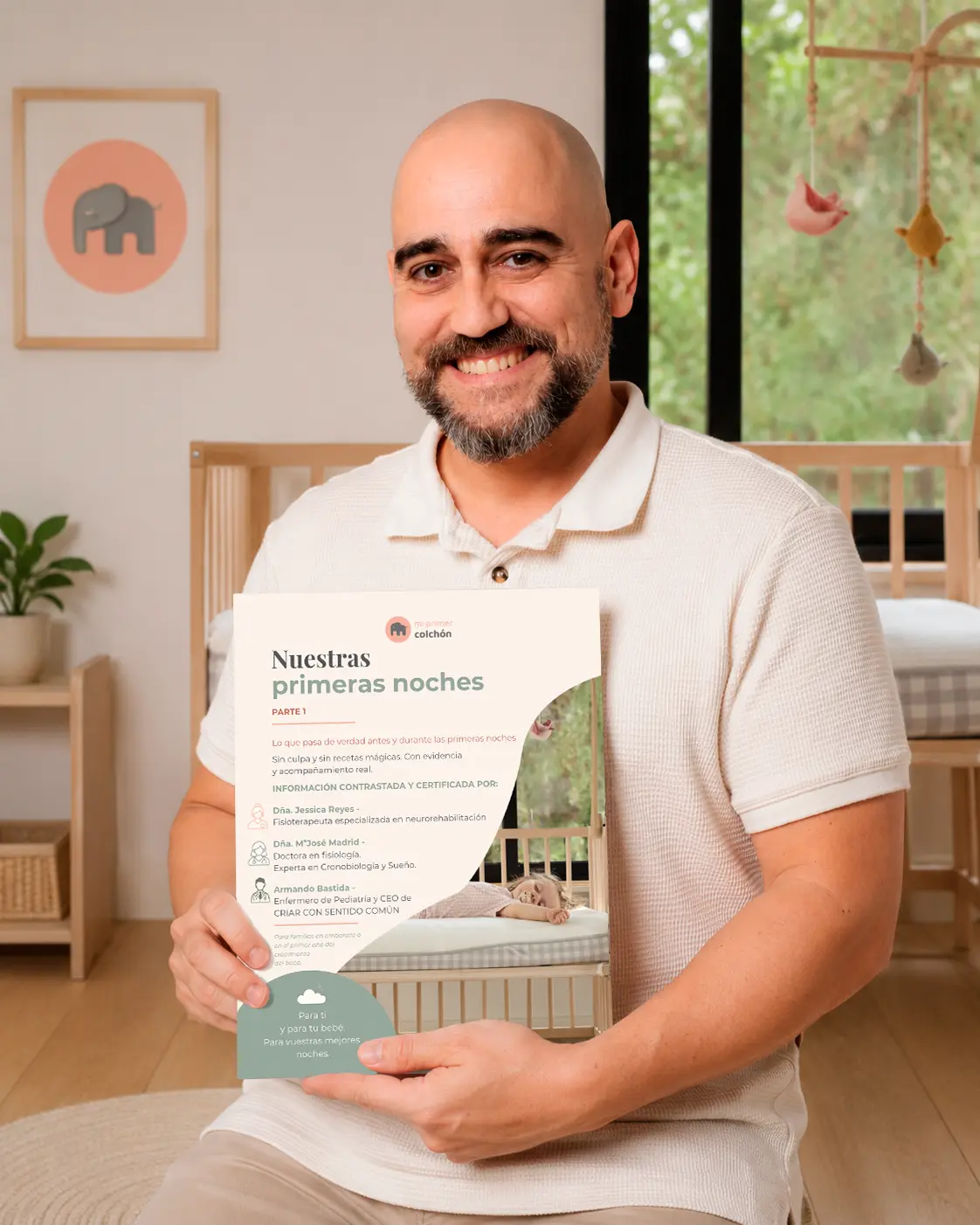 Armando Bastida sosteniendo la guía «Nuestras primeras noches» en la habitación del bebé